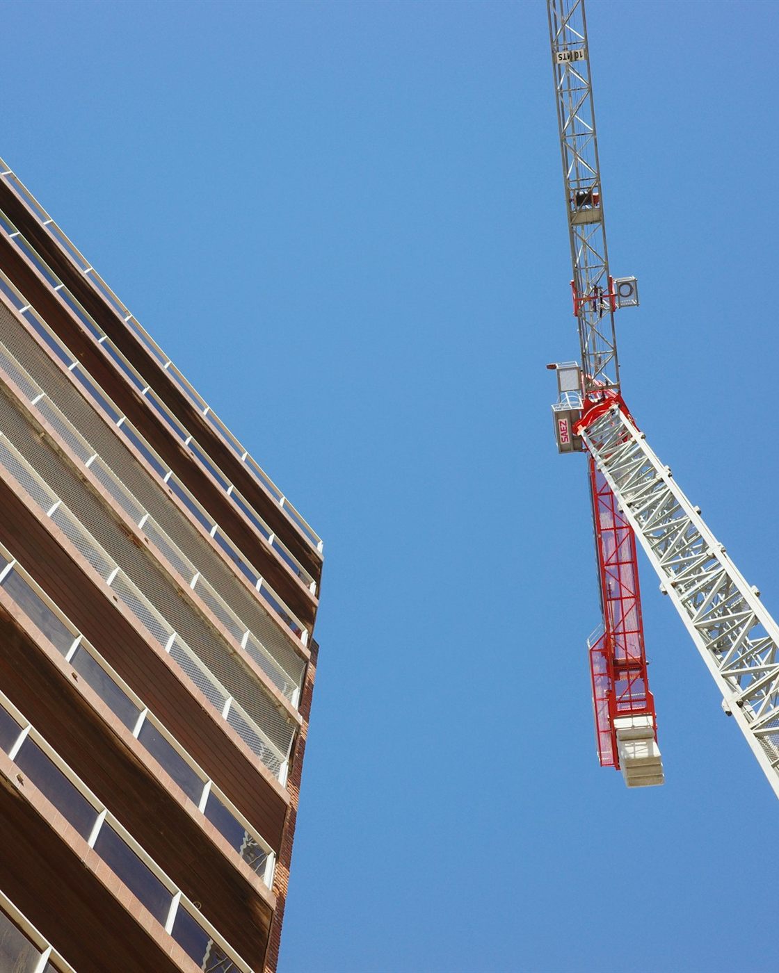Immeuble moderne et grue de chantier sous un ciel bleu.